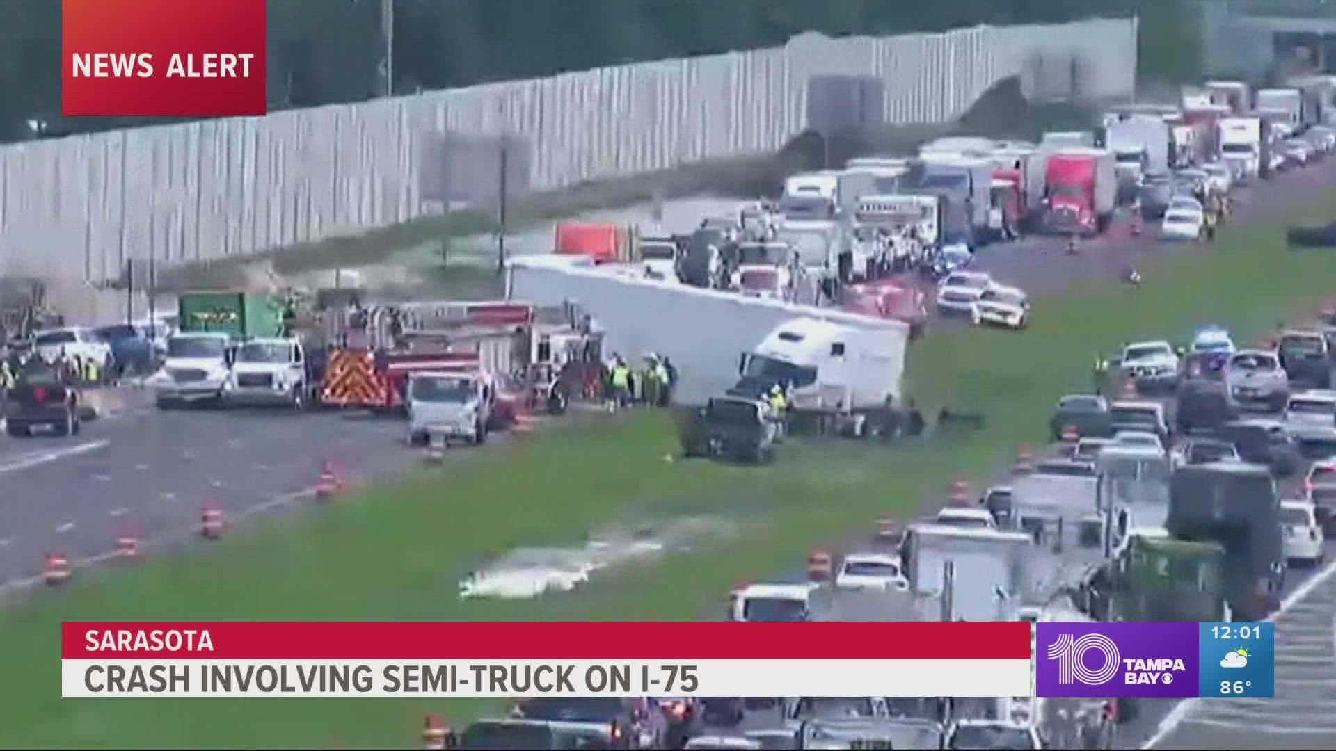 Florida Department of Transportation cameras shows the front of the semi-truck in the grassy median while the back is blocking lanes.