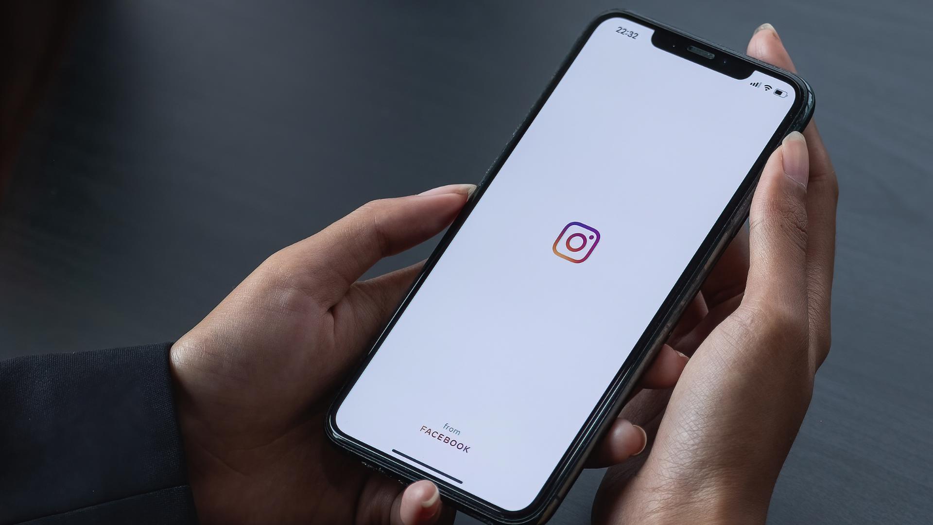 CHIANG MAI, THAILAND - APR 6 2021: Woman hand holding iphone with logo of instagram application