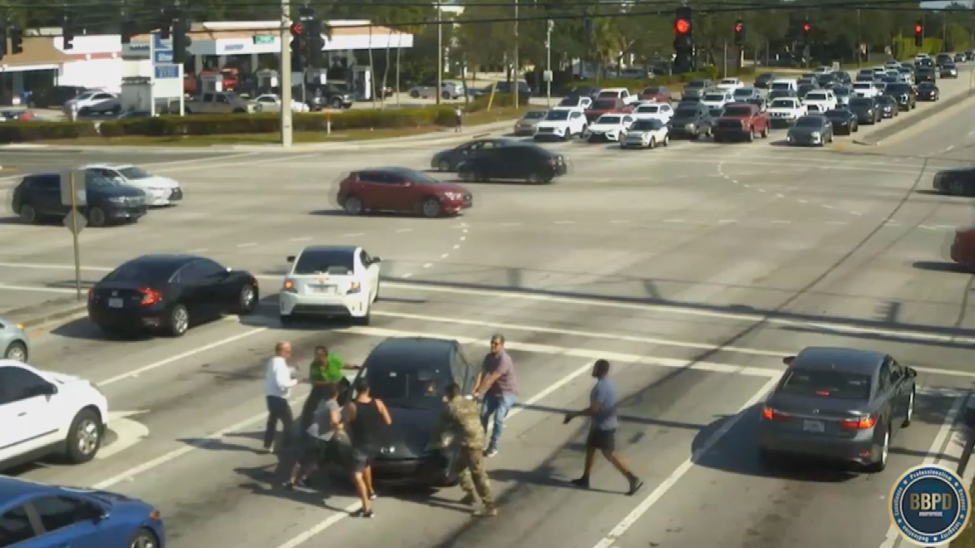 Video shows the car crossing the intersection before multiple people worked to push and hold the car in place.